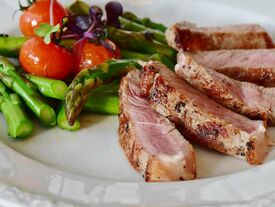 assiette avec légumes (asperges, salade, tomates) et morceaux de viande
