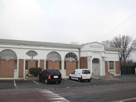 La façade et une partie d'un parking de la salle des fêtes
