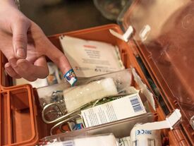 une trousse de premier secours avec une main dont un doigt a un pansement
