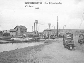 Carte postale de la fin du 19ème siècle, en noir et blanc représentant les écluses jumelles au niveau du Canal de la Scarpe. En premier plan un tracteur à traction électrique.