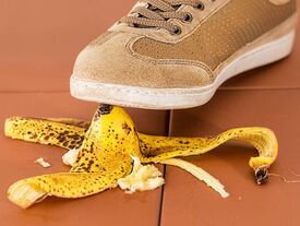Une chaussure qui va poser son pied sur une peu de banane